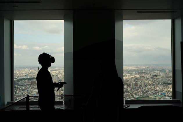 With a view of Tokyo's cityscape, a man wearing a VR headset plays a video game at the Sky Circus Sunshine 60 observatory, in Tokyo. (Jae C. Hong / AP) With a view of Tokyo's cityscape, a man wearing a VR headset plays a video game at the Sky Circus Sunshine 60 observatory, in Tokyo. (Jae C. Hong / AP)