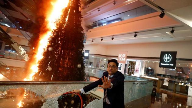 A man reacts as he tries to extinguish a burning Christmas tree at Festival Walk mall in Kowloon Tong, Hong Kong. Protesters have torched vehicles and buildings, hurled petrol bombs at police stations and trains, dropped debris from bridges on to traffic below and vandalised shopping malls and campuses, raising questions about how and when more than five months of unrest can be brought to an end. (Thomas Peter / REUTERS)