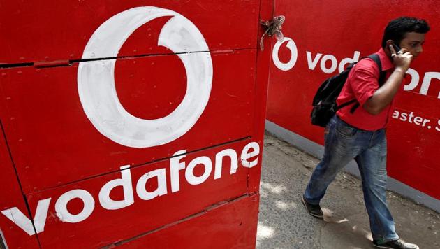 FILE PHOTO: A man speaks on his mobile phone as he walks past logos of Vodafone painted on a roadside wall in Kolkata May 20, 2014. REUTERS/Rupak De Chowdhuri/File Photo(REUTERS)