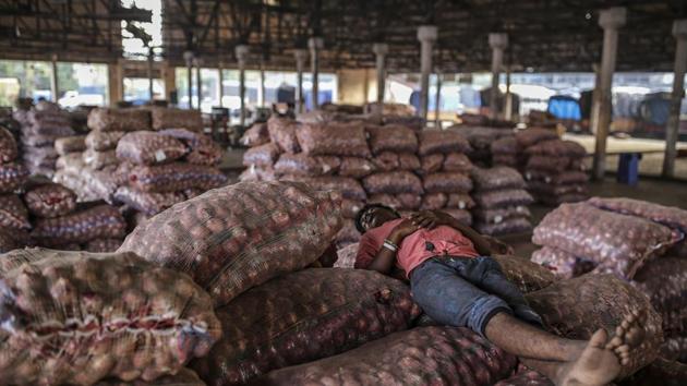 A worker sleeps on sacks of onions at the Vashi Agricultural Produce Market Committee (APMC) wholesale market in Mumbai.(Bloomberg)