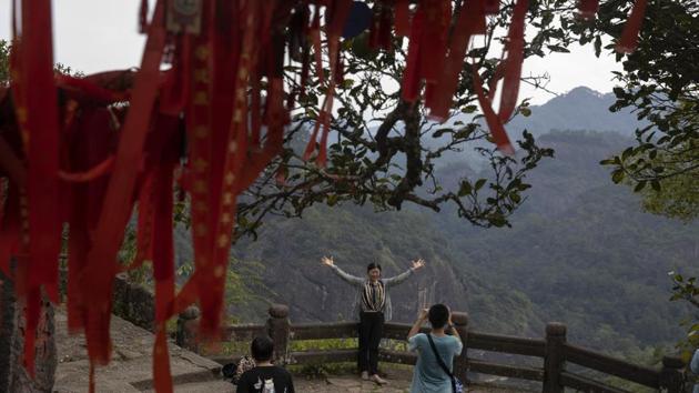 A visitor poses for a photo on Tianyou peak in Wuyishan. Yellowstone is widely considered the world’s first national park. After it was created in 1872, the U.S. government forced the Native Americans who lived in the area to resettle outside the park boundaries, in keeping with 19th-century notions of wilderness protection. But countries that establish park systems in the 21st century now must consider how best to include local populations in their planning. (Ng Han Guan / AP)