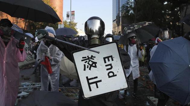 A protestor bangs a metal rod on a street sign during a confrontation at the Hong Kong Polytechnic University in Hong Kong. Demosistō, a pro-democracy organisation, said Saturday’s clean-up operation could set a “grave precedent” if the city’s government invites the military to deal with internal problems.  (Kin Cheung / AP) 