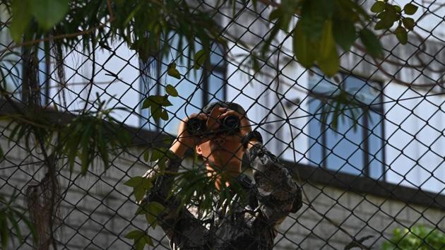 A Chinese People's Liberation Army (PLA) soldier uses binoculars by the perimeter fence of the PLA Hong Kong Garrison barracks, located near the Hong Kong Polytechnic University. Hong Kong did not request assistance from the PLA and the military initiated the operation as a “voluntary community activity”, a spokesman for the city’s government said. (Philip FONG  / AFP) 