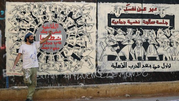 Lebanese artist and rights activist Selim Mawad seen in front of his mural paintings in central Beirut. “This city has become an icon of capitalism,” said Mawad. He jumped onto a plastic barricade to retouch a mural of stylised bulls alongside the slogan: “What is the future of our revolution?” (JOSEPH EID / AFP)
