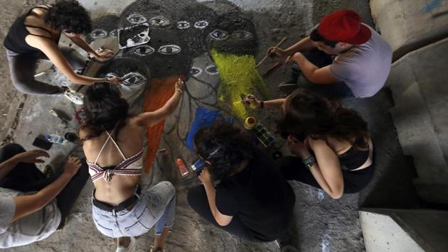 Lebanese anti-government protesters paint a graffiti on the ground in central Beirut. “People say, ‘I can’t touch this building, I can’t live there, so I’ll leave my mark on it’,” the paint-spattered artist said. One day, assailants attacked the protesters in the area where Mawad was painting his mural. He was beaten and his bicycle stolen.“Give back the stolen money -- and don’t forget the bike,” he later painted next to a picture of a bull brandishing a red bicycle. (JOSEPH EID / AFP)
