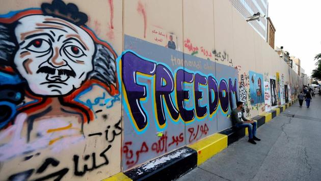 A man sits under a wall covered with graffitis. Artists hope that these paintings will be preserved and it will be a memory of an uprising. (JOSEPH EID / AFP)