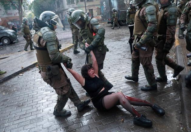 Riot police officers detain Camila Miranda after she was shot with 6 rubber bullets, 4 of which pierced her skin during a protest which she was demonstrating at against Chile's government in Santiago, Chile. (Henry Romero / REUTERS) Riot police officers detain Camila Miranda after she was shot with 6 rubber bullets, 4 of which pierced her skin during a protest which she was demonstrating at against Chile's government in Santiago, Chile. (Henry Romero / REUTERS)