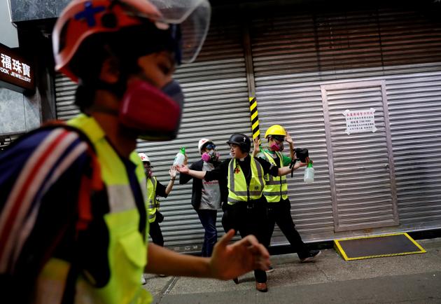 Pastor Alan Keung and first aid volunteers gesture as riot police advance to disperse protesters during an anti-government protest in Hong Kong. Wearing cross and clerical collar, Hong Kong pastor Alan Keung says he brings God’s love to the masses in a different way these days, using saline to wash away tear gas fired at crowds of protesters on tumultuous streets, or helping injured police. (Kim Kyung-Hoon / REUTERS)