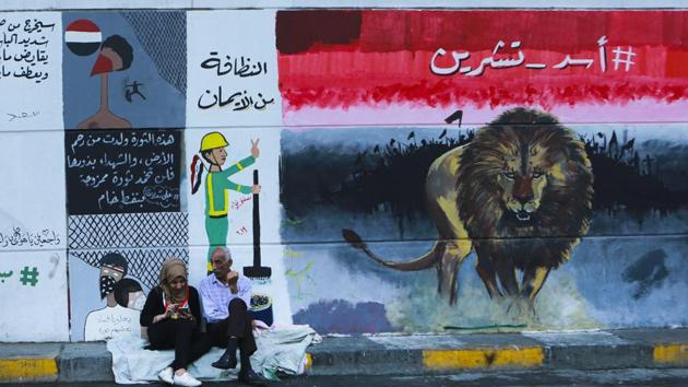Young protesters, men and women, throng the tunnel — actually a long underpass, most of which is open to the air except for enclosed portions directly beneath Tahrir — and pass time there hanging out or taking selfies in front of the murals. Caricatures on the walls mock Iraqi politicians; other paintings praise the tuk tuks; a woman with an Iraqi flag on her cheek flexes her bicep, recreating the famed U.S. “We Can Do It” poster; faces in drawings shout in anger or pain. (Hadi Mizban / AP) Young protesters, men and women, throng the tunnel — actually a long underpass, most of which is open to the air except for enclosed portions directly beneath Tahrir — and pass time there hanging out or taking selfies in front of the murals. Caricatures on the walls mock Iraqi politicians; other paintings praise the tuk tuks; a woman with an Iraqi flag on her cheek flexes her bicep, recreating the famed U.S. “We Can Do It” poster; faces in drawings shout in anger or pain. (Hadi Mizban / AP)