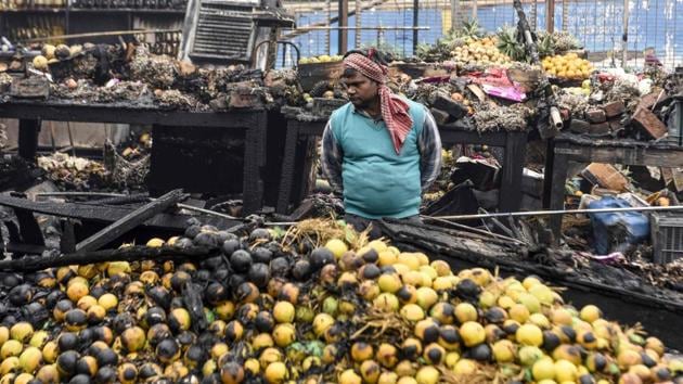 A shopkeeper looks at a pile of burnt fruit after a fire broke out at a fruit market in Amritsar, Punjab. (Narinder Nanu / AFP)