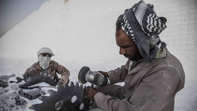 A labourer sharpens the blade of a stone saw at the limestone extraction quarry site. Once fed and ready for the day’s task, they don goggles and wrap scarves around their faces in an attempt to keep out the clouds of white powder thrown up by the whirring machines. (Khaled Desouki / AFP)