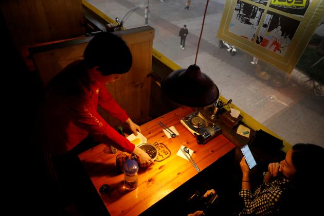 Kim Jae-hoon clears a table at the pub where he works in Suwon. “I can’t complain that we have different starting lines,” said Kim Jae-hoon, 26, who also lives in a cubicle. “But it makes me angry that there are people who are getting help improperly. It’s OK that someone was studying when I had to be working, but the fact that they are getting improper help makes me angry.” (Kim Hong-Ji / REUTERS)