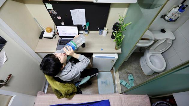 Kim Jae-hoon drinks water as he sits in his cubicle, called a goshi-won, where he lives in Suwon, South Korea. Such sparsely furnished rooms, in premises called goshi-won, were previously mostly used by less well-off students to temporarily cut themselves off from the outside world while they studied for civil service job tests. (Kim Hong-Ji / REUTERS)