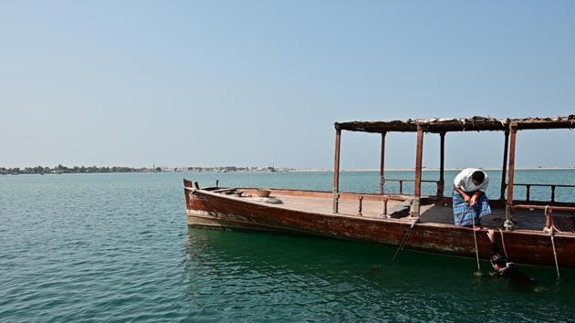 Abdullah al-Suwaidi is pictured inside the water near his dhow. Once done, between one and two minutes, he tugs at the rope, and his assistant pulls him up to the surface. His tools are simple: a sea rock that hangs off his foot to weigh him down, a nose plug or ftaim, and a basket. (Guiseppe Cacace / AFP) 