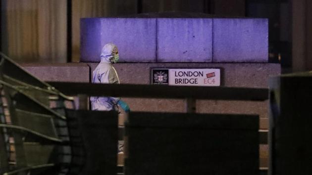 A police forensic officer walks by a sign where a man was shot dead by police on London Bridge following a stabbing incident that left several people wounded, on November 29. (Matt Dunham / AP)