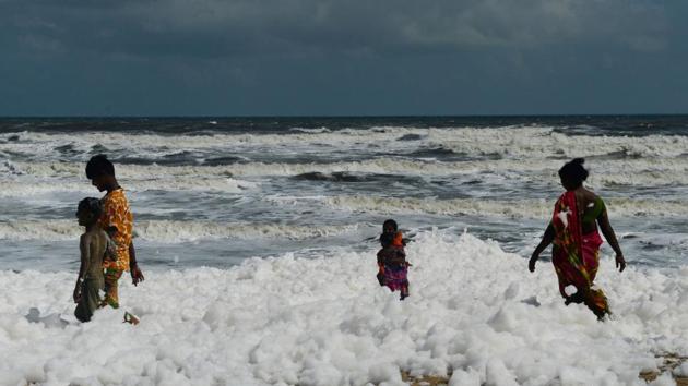 People are seen walking on foam that has formed due to increased pollution, in Chennai, Tamil Nadu. (Arun Sankar / AFP)