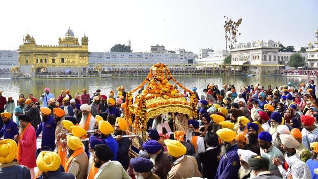 Devotees carry Sri Guru Granth Sahib Ji, the holy book of the Sikhs, in a special golden palanquin as they circumambulate the holy pond during a religious procession on the eve of the martyrdom day of Guru Tegh Bahadur, the ninth Sikh Guru, at Golden Temple, in Amritsar, Punjab. (Sameer Sehgal / HT Photo)
