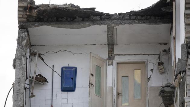 A part of a collapsed building stands in Thumane. Many buildings only partially collapsed, left gaping holes where walls and floors should be, bedroom doors opening into the void, bathroom fixtures dangling from walls in a stark reminder of the powerful and destructive force of nature. (Petros Giannakouris / AP)