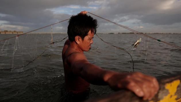 Domingo Martinez hauls in crab whilst fishing in the surrounding area of Sitio Pariahan. “If you work hard here, you will survive. You only have to jump on the sea to catch food. In land, you can work hard and still not have enough,” Mary Jane said. Her husband, Domingo, said leaving was not an option, because there is nowhere to go. (Eloisa Lopez / REUTERS)