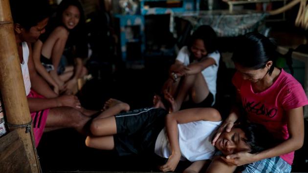 The Martinez family spend time together in their bamboo hut. They once tried to rent an apartment in a nearby town, but moved back shortly after. “Our livelihood is here,” Domingo said. “If we are asked to move inland, it would be difficult to make a living. What if we become beggars there?” (Eloisa Lopez / REUTERS)