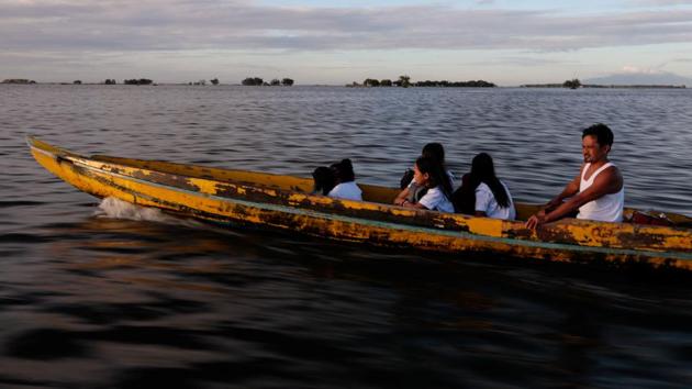 Domingo Martinez, 40, drives his daughters Danica, 16, and Cindy, 14, to school on his boat, in a nearby town in Bulakan. Danica and her siblings take this 30-minute boat ride to school, sometimes with uniforms drenched by big waves. “It seems scary to look at, but you get used to living like this,” she said. “It’s difficult, but also fun.” (Eloisa Lopez / REUTERS)