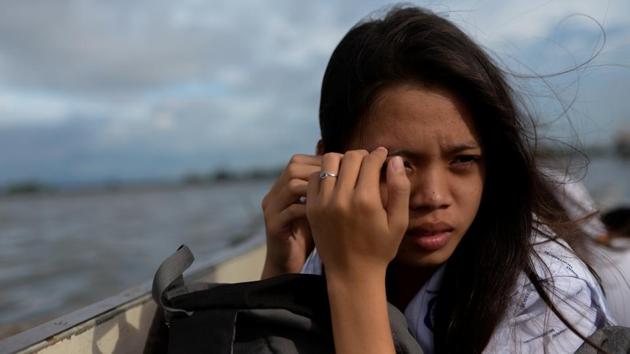 Danica Martinez, 16, shields her face away from the sun as she travels home from school by boat. Danica grew up in a house that grows taller every few years. Her father raises the stilts of their bamboo hut so water from the sea doesn’t reach the floor. They live in Sitio Pariahan, a coastal village in the Philippines that was once an island, and is now without land. (Eloisa Lopez / REUTERS)