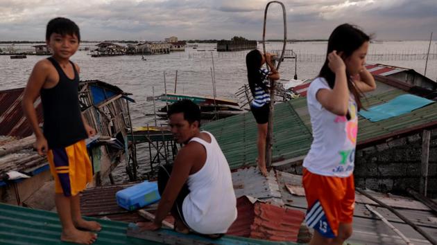 The Martinez family spend time together on the roof of their bamboo hut. Much of the destruction happened when Typhoon Nesat struck in 2011, bringing waves Danica said were as big as houses. She saw how the huts were pulled into the sea, one by one, as she and her siblings held onto bamboo poles. Their school was also destroyed, and left only with walls. More than 50 families left and never returned. (Eloisa Lopez / REUTERS)