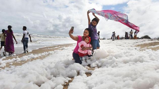 A family takes a selfie in the polluted waters of the Bay of Bengal. Children have been playing and taking selfies in the clouds of white suds on Marina Beach, even though they give off an acrid smell and fishermen have been told not to go into the sea nearby. (PTI)