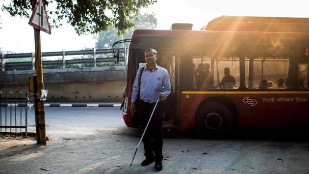 Vinod Kumar Sharma gets off a public bus while on his way. Sharma, like many other blind Indians, also battles a dire lack of opportunities in education and employment for disabled people. Many are forced to beg or turn to charity to make ends meet. (Xavier Galiana / AFP)