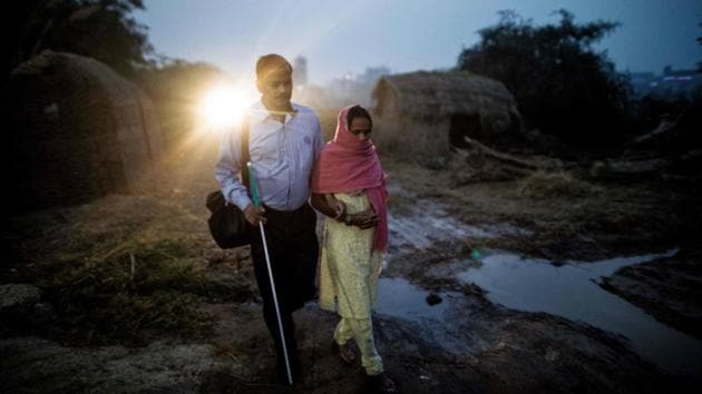 Sharma is led by his wife Indrapti (R) along a road to Asaoti station in Asaoti. “Once they come out and know they can do different things, that itself is a big exposure to them... Every story of success is an inspiration for many others.” (Xavier Galiana / AFP)