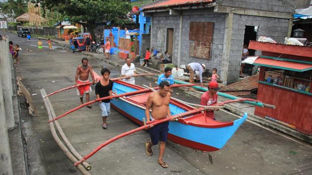Residents carry to safety a wooden boat in Legaspi City. Government offices and schools were closed in affected areas and utilities firms appealed for patience ahead of anticipated power outages. The coastguard halted commercial sea travel in affected areas stranding more than 6,000 travellers along with thousands of cargo ships and smaller watercraft in the archipelago nation. (Razvale Sayat / AFP)