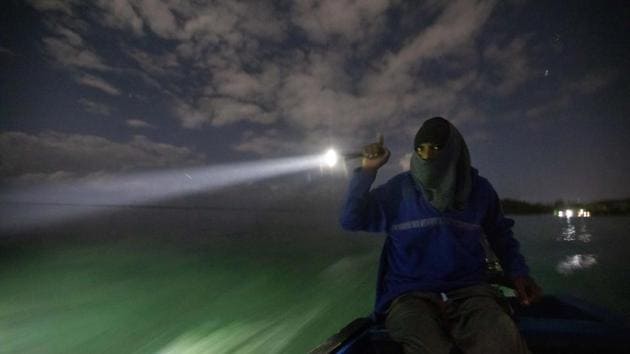 White River Fish Sanctuary warden Mark Lobban shines a spotlight on the protected reef while patrolling the no-take zone for illegal fishermen. That night, two other flashlights scanned the water — but these were searching for people illegally fishing in the White River Fish Sanctuary, about 9 kilometers away. (David Goldman / AP)