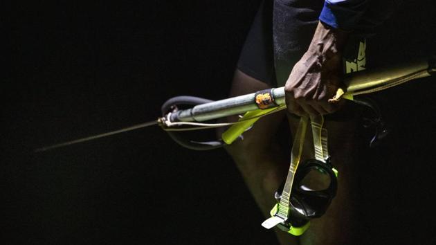 Nicholas Bingham stands at the water’s edge before jumping in. Spearfishing at night in Jamaica is illegal, especially in the sanctuaries set up to protect the island country’s endangered coral reefs and replenish fish stocks. The restrictions have taken a toll on many Jamaicans’ livelihoods, in a place where jobs can be scarce. (David Goldman / AP)