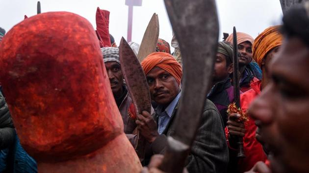 Devotees holding knives look on as mantras are sung ahead of sacrificial offerings. After the ceremonial slaughter of the five animals, some 200 butchers with sharpened swords and knives walked into a walled arena bigger than a football field that held several thousand buffalo as excited pilgrims climbed trees and walls to catch a glimpse. (Prakash Mathema / AFP)