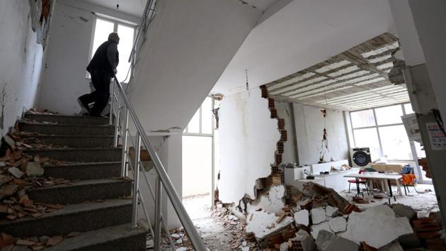 A man enters his home, damaged in a 6.4 magnitude quake that hit the Balkan country before dawn on November 26 was the most deadly and destructive in decades, to take his belongings in the earthquake hit city of Durres, western Albania. (Gent Shkullaku / AFP)