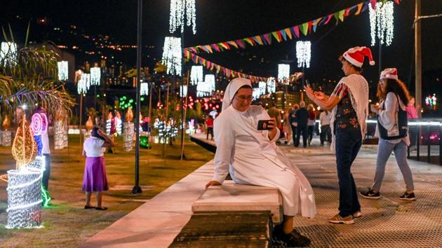 A nun looks at her mobile phone as she visits the area along the Medellin river after it was decorated for the Christmas season, in the Colombian city of Medellin. (Joaquin Sarmiento / AFP)