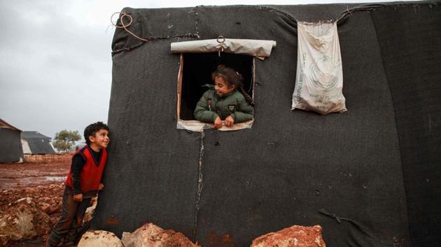 A boy and a girl looking out the window of a tent exchange glances, at a flooded camp for displaced Syrians near the village of Killi in the north of the northwestern Idlib province, Syria. (Aaref Watad / AFP)