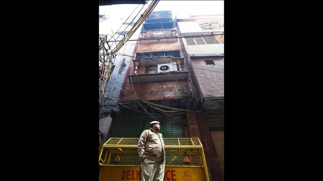 A police personnel stands guard in front of the building today. The Delhi Fire Services said that factory did not have a no-objection certificate. Police arrested the building owner, Mohammed Rehan and his manager, Furkan, and charged them with culpable homicide and attempt to culpable homicide. The crime branch has taken over the probe and are trying to identify the contractors running the factories. (Amal KS / HT Photo)
