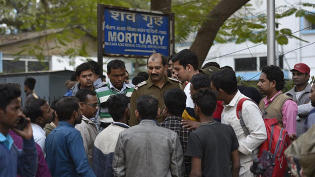A police officer shows photographs to the family members of the victims outside after the fire, outside Lok Nayak hospital. The North Delhi Municipal Corporation said the factory was illegal. The Anaj Mandi area, which was originally residential, was declared ‘mix land use’ in 2006 — only commercial activities such as grocery stores and ‘household’ industries (employing not more than nine people and using not more than 11 kW power) are allowed. (Burhaan Kinu / HT Photo)