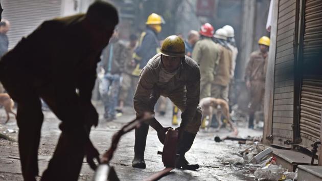 Firefighters in action at the spot. At least 30 fire tenders arrived quickly but the narrow single approach to the building made it impossible for the bulky engines to reach close to the building. Rescuers had to move dozens of rickshaws and bikes so that the firemen could make their way through the labyrinthine roads enmeshed with electrical wiring. (Sanchit Khanna / HT Photo)