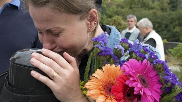 Tetyana kisses the ashes of her husband goodbye in Kyiv. Tetyana's husband Alexander passed away a year after returning from captivity in the Donetsk region, where he was held by pro-Russian militias in 2018. (Zoya Shu / AP)