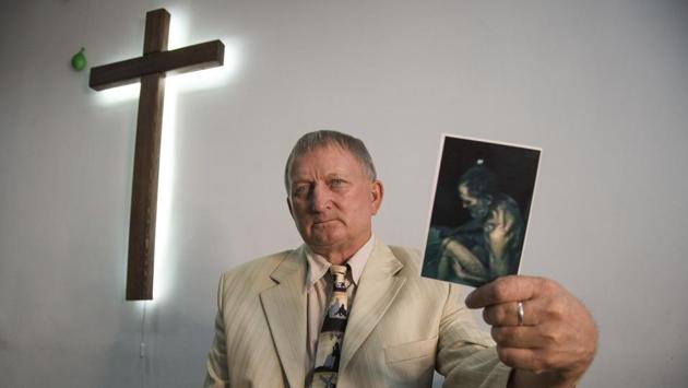 Vitaly Paraskun holds a photo of himself, taken right after he was released from of captivity, in a church in Kyiv where he serves, Ukraine. Paraskun was captured in October 2014 by a gang of Cossacks in the Luhansk region, where he, an Evangelical priest, was doing missionary work. Paraskun spent 199 days in an unheated basement and was regularly tortured. (Zoya Shu / AP)