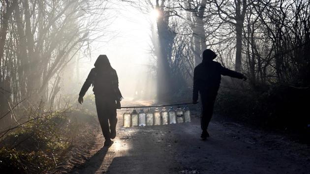 Illegal migrants carry a resupply of water from a nearby well. Local authorities say the 350 migrants will be temporarily housed at an official centre outside the capital Sarajevo -- a destination far from the Croatian border that the migrants want to cross to reach the European Union. (Elvis Barukcic / AFP)