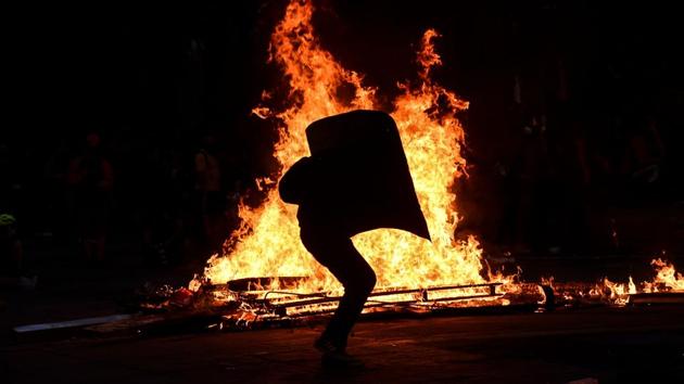 A demonstrator holds a shield in front of a bonfire during a protest. Attacks by masked protesters on police have a particular resonance in Chile, where leftist groups clashed with military dictator Augusto Pinochet’s security forces from 1973 to 1990, a period that has helped “romanticize” violent resistance of tyranny in the country. “However, the violence the country has seen since October 18 is unprecedented in democracy,” said Fernandez. (Martin BERNETTI / AFP) A demonstrator holds a shield in front of a bonfire during a protest. Attacks by masked protesters on police have a particular resonance in Chile, where leftist groups clashed with military dictator Augusto Pinochet’s security forces from 1973 to 1990, a period that has helped “romanticize” violent resistance of tyranny in the country. “However, the violence the country has seen since October 18 is unprecedented in democracy,” said Fernandez. (Martin BERNETTI / AFP)