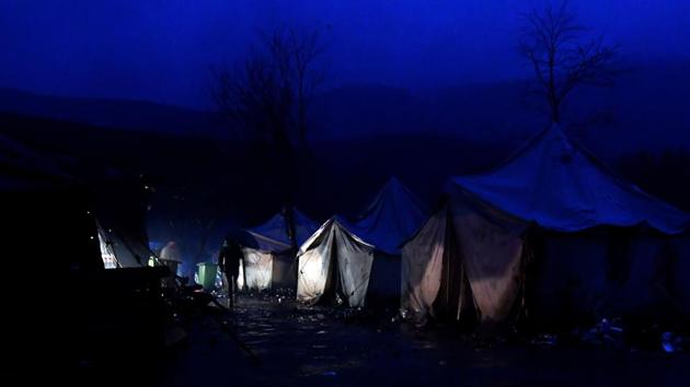Migrants walk among tents as night falls over the improvised migrants camp “Vucjak”, in the outskirts of Northern-Bosnian town of Bihac. Bosnian authorities have begun to move several hundred migrants out of the ramshackle camp near the Croatian border following international condemnation of the site’s inhumane conditions. (Elvis Barukcic / AFP)