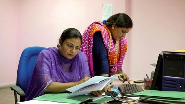 Amritpal Kaur (L) and Reena Mehla work together at a desk in the regional passport office in Chandigarh. The wives say many of the men demand and often get tens of thousands of dollars in dowry, despite the ancient practice being illegal. The husbands can use that money to establish themselves overseas and obtain permanent residency or a new passport, leaving their wives and children behind in limbo. (Anushree Fadnavis / REUTERS)