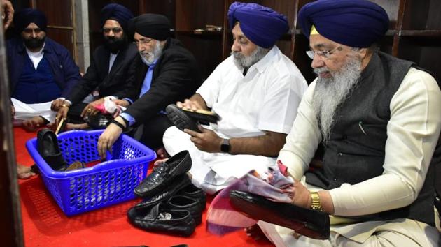 Shiromani Akali Dal president Sukhbir Singh Badal flanked by Shiromani Gurdwara Parbandhak Committee (SGPC) chief Gobind Singh Longowal and former minister Daljit Singh Cheema polishing shoes as(Sameer Sehgal/HT)