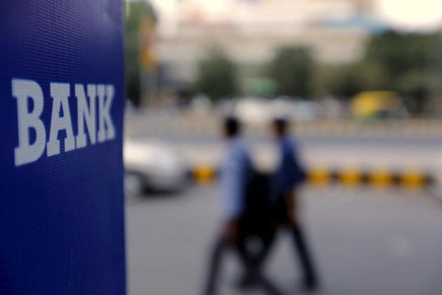 Commuters walk past a bank sign along a road in New Delhi.(REUTERS) Commuters walk past a bank sign along a road in New Delhi.(REUTERS)