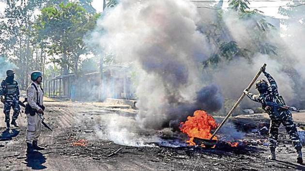 An Army official attempts to douse a burning tyre during protests against the Citizenship Amendment Bill in Dibrugarh on Thursday.(Photo: PTI)