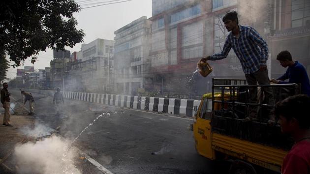 Police clear road blocks as a man tries to douse a fire set by protesters in Guwahati, Assam, on Thursday.(AP Photo)